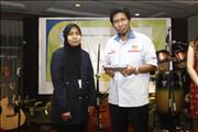 Pn. Rosnani handing a gift to En. Kamaruddin (SKM)